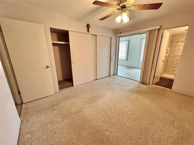 an empty room with closet and a ceiling fan