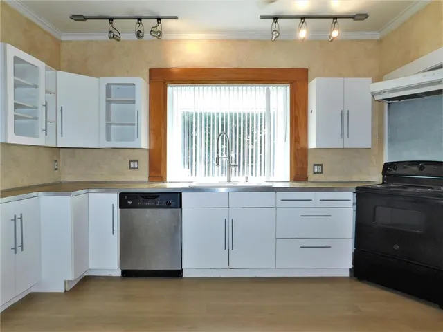 a kitchen with granite countertop white cabinets and window
