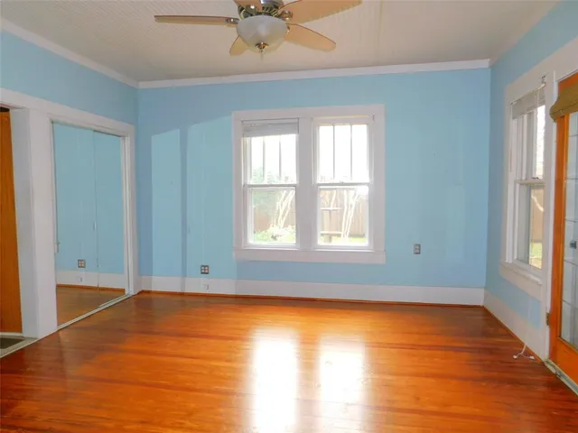 an empty room with wooden floor and windows