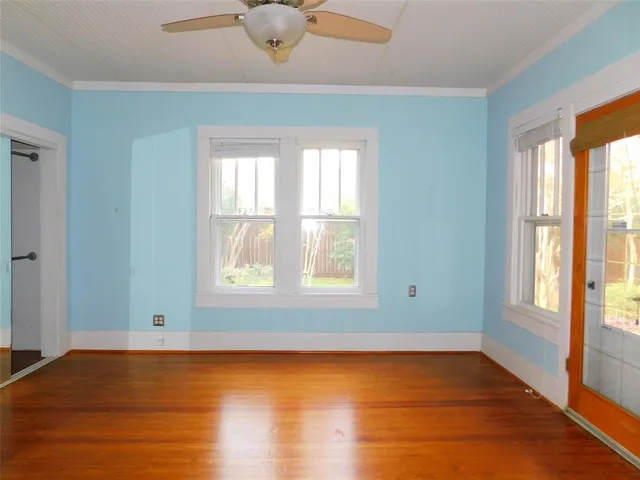 a view of an empty room with wooden floor and a window