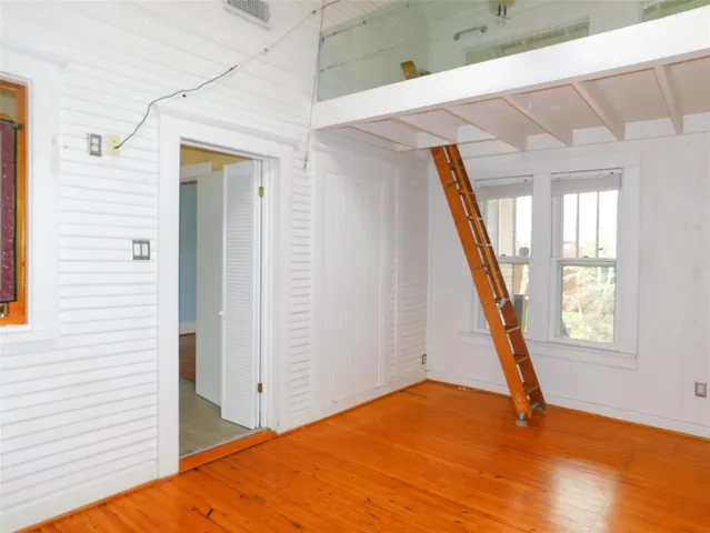 a view of an empty room with wooden floor and stairs