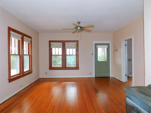 a view of an empty room with wooden floor and a window
