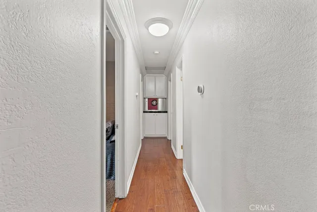 a view of a hallway with wooden floor and a bathroom