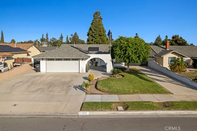 an aerial view of a house with yard and trees in the background