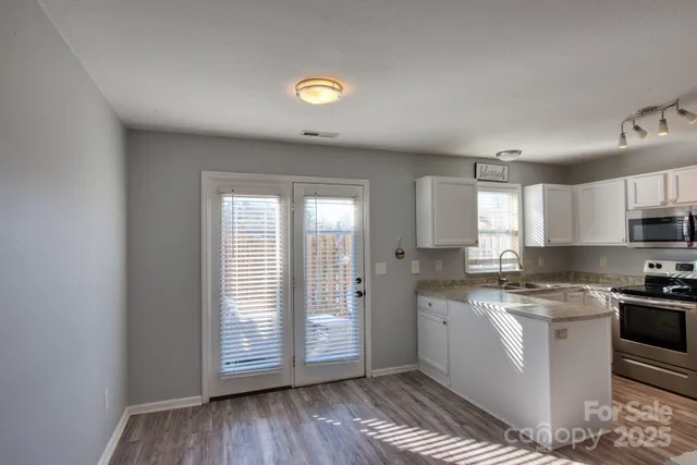 a kitchen with a sink a stove cabinets and wooden floor