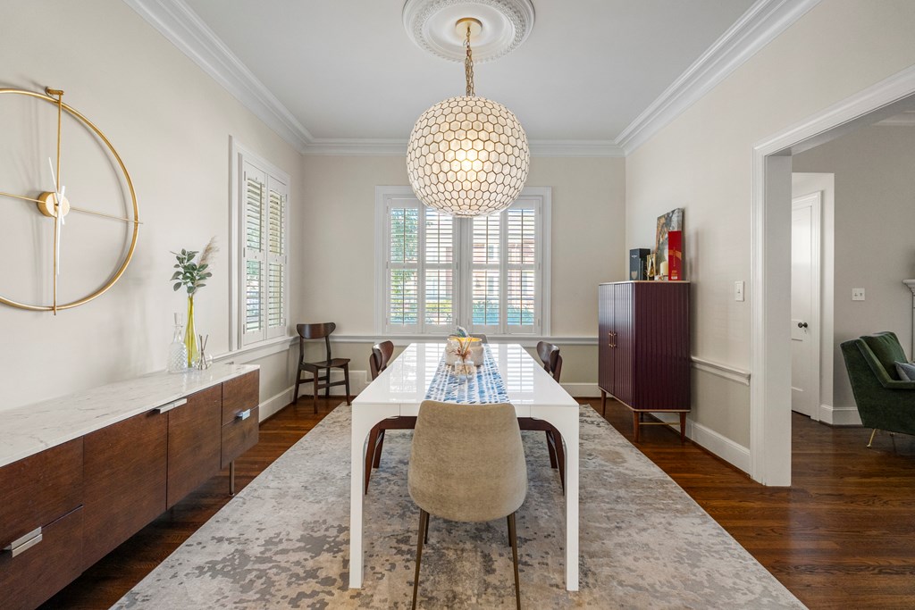 2134 13th Street Columbus, GA 31906 - Photo 8 of 27 a dining room with wooden floor a chandelier a wooden table and chair