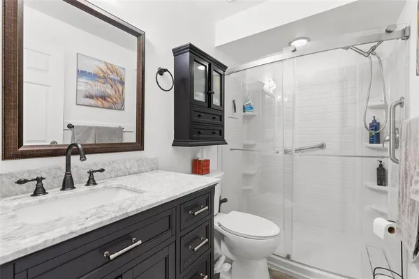 a bathroom with a granite countertop sink toilet and shower