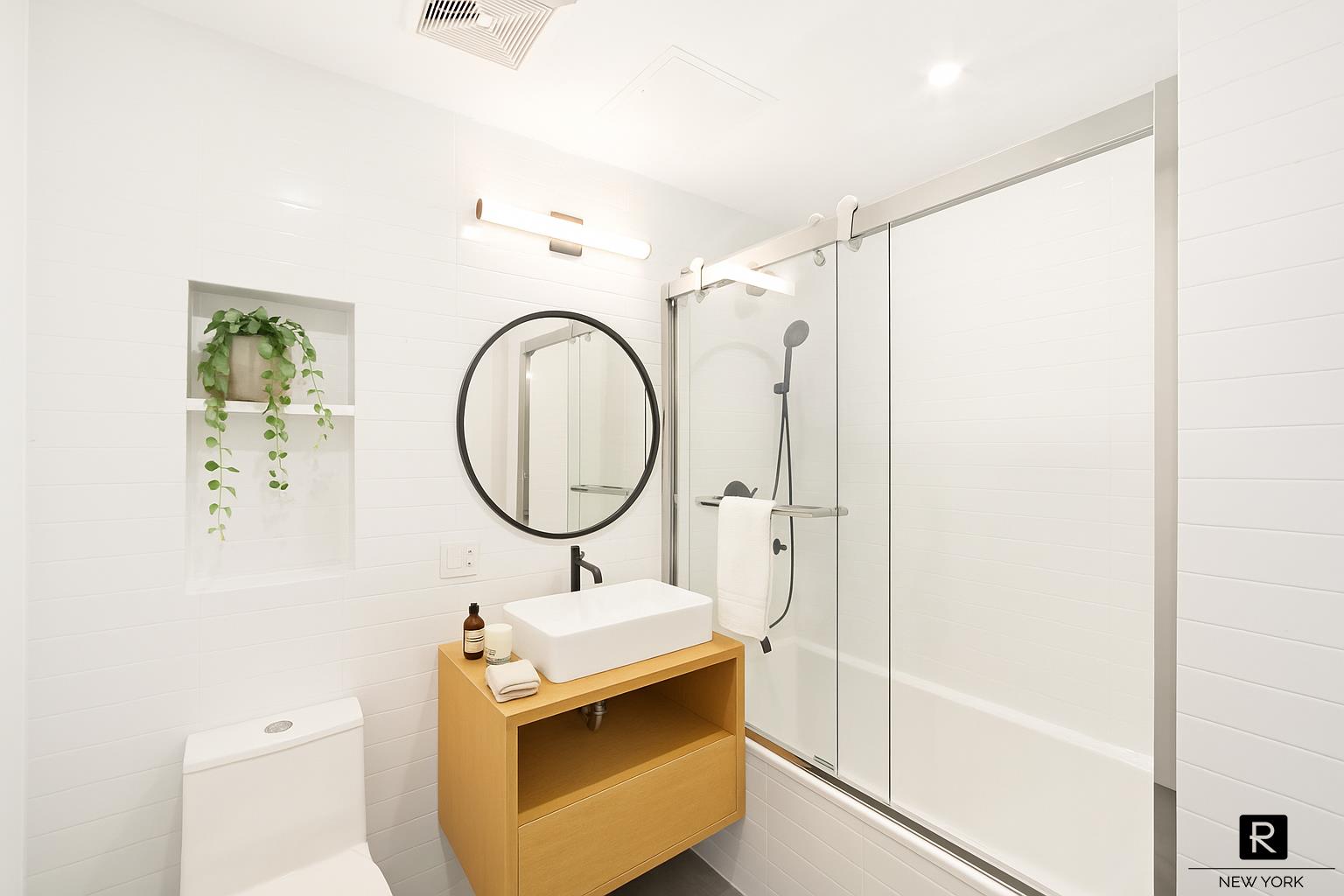 340 Metropolitan Avenue, Unit 5B Brooklyn, NY 11211 - Photo 8 of 12 a bathroom with a sink mirror vanity and a shower
