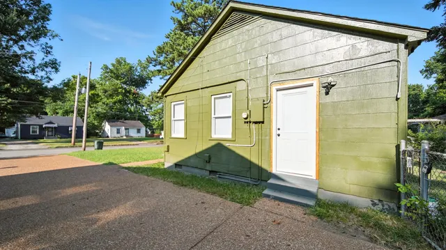 a view of yellow house with a yard and plants