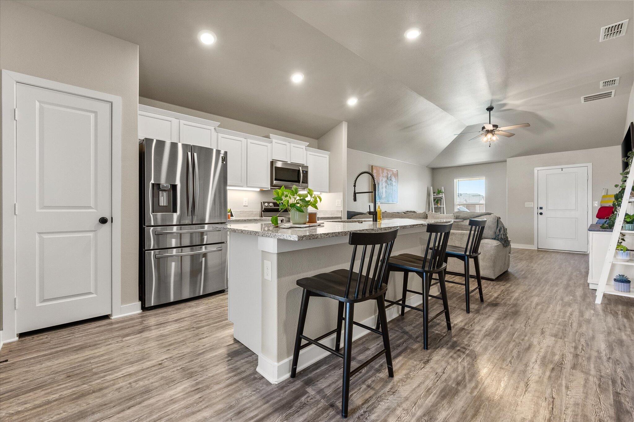 1902 137th Street Lubbock, TX 79423 - Photo 13 of 27 a kitchen with stainless steel appliances a dining table chairs refrigerator sink and cabinets