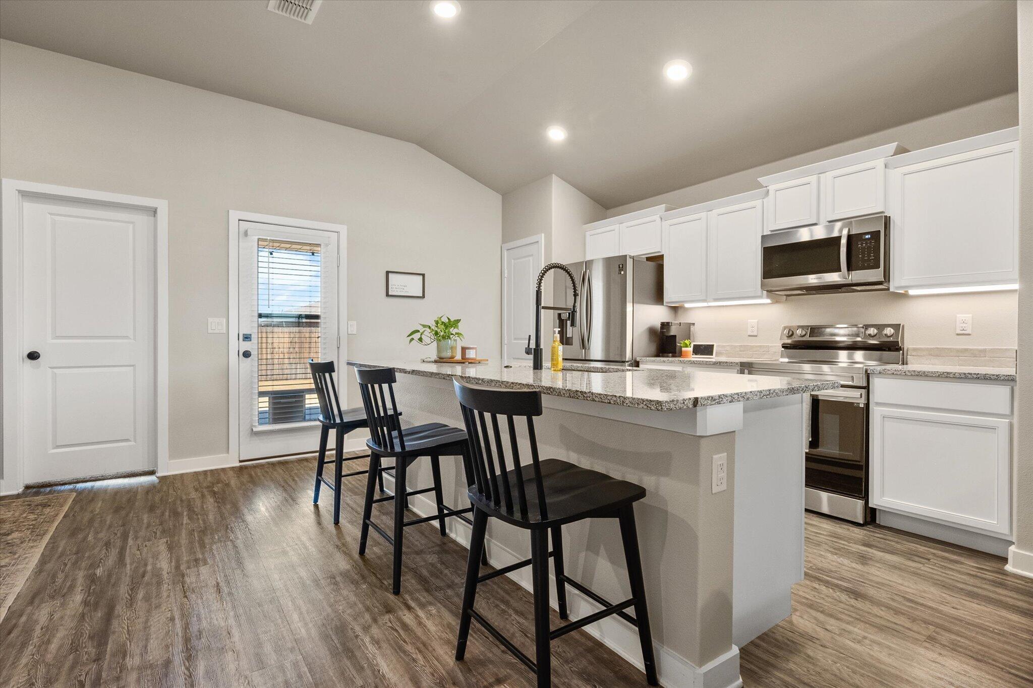1902 137th Street Lubbock, TX 79423 - Photo 10 of 27 a kitchen with stainless steel appliances a dining table chairs microwave and sink