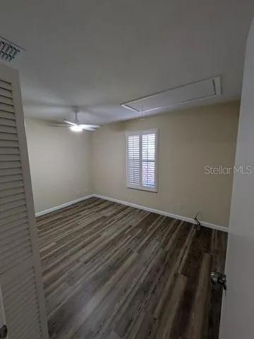 a view of empty room with wooden floor and fan