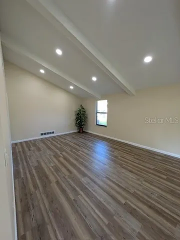 a view of empty room with window and wooden floor
