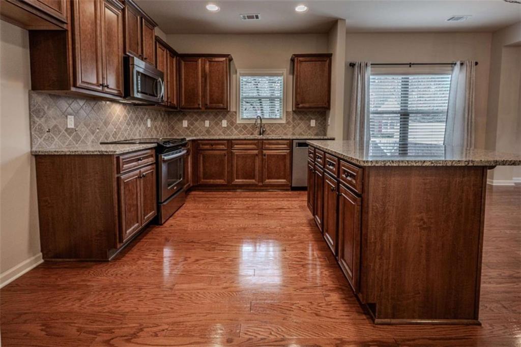 205 Heritage Stroll Athens, GA 30606 - Photo 5 of 30 a kitchen with stainless steel appliances granite countertop a stove a sink dishwasher and a microwave oven with wooden cabinets