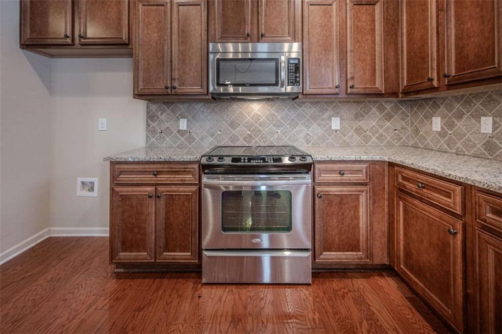 205 Heritage Stroll Athens, GA 30606 - Photo 8 of 30 a kitchen with granite countertop wood cabinets and stainless steel appliances