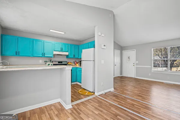 a kitchen with granite countertop a refrigerator and a stove top oven