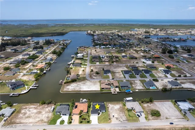 an aerial view of ocean and residential houses with outdoor space