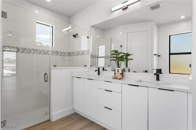 a bathroom with a double vanity sink mirror and shower