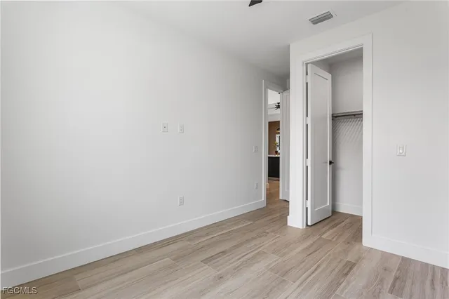 a view of an empty room with wooden floor and closet