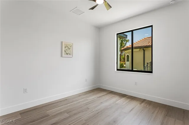 an empty room with a window and a ceiling fan