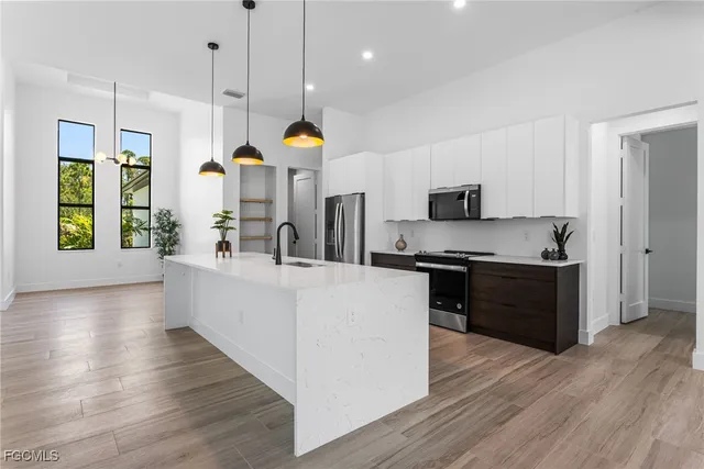 a large kitchen with stainless steel appliances kitchen island a large counter top a stove and a wooden floors