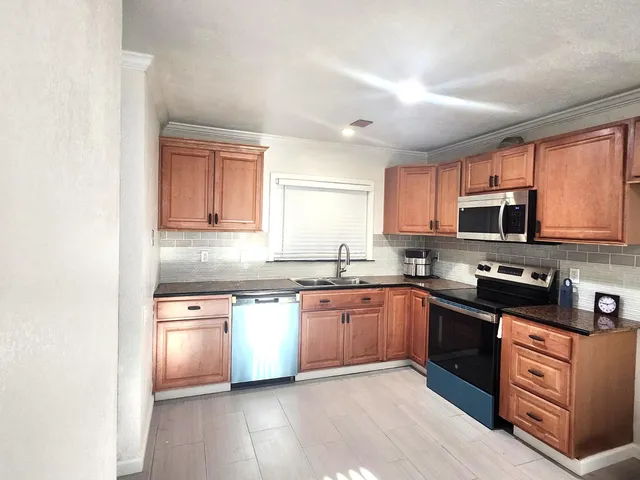 a kitchen with stainless steel appliances granite countertop a stove top oven a sink dishwasher and a refrigerator