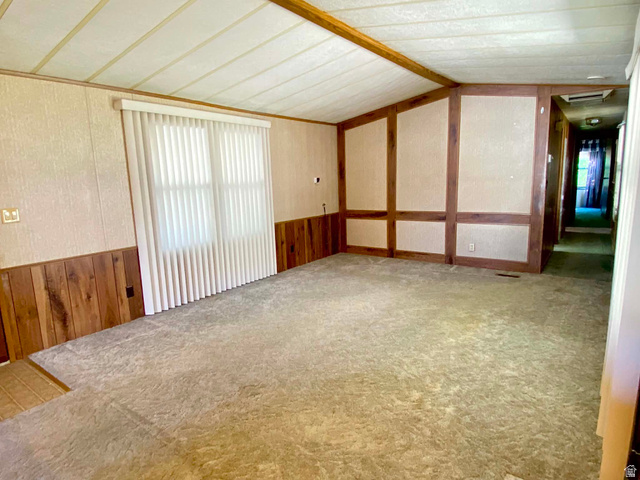 1111 North 2000 West, Unit 147 Ogden, UT 84404 - Photo 6 of 12 Carpeted living space featuring vertical blinds, paneled walls, and wood-finish ceiling beams
