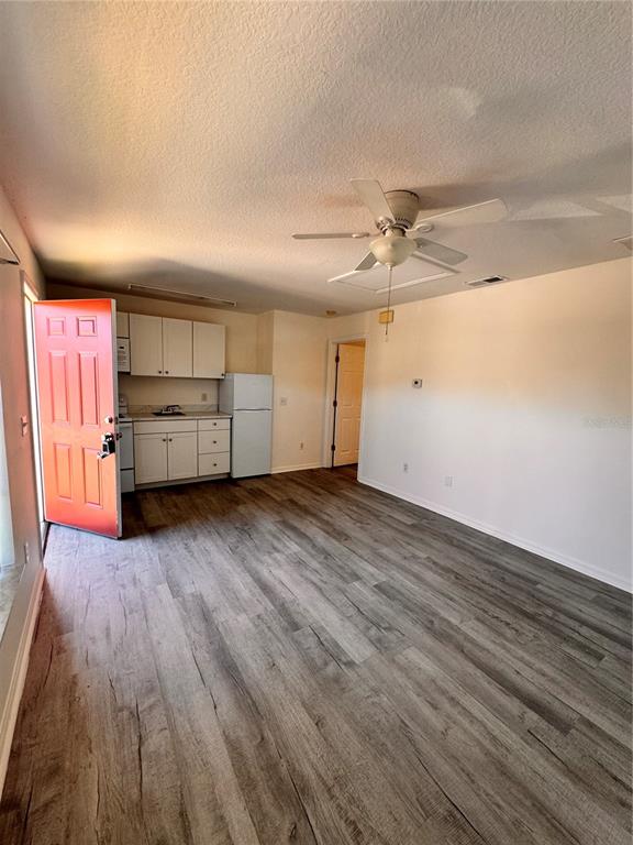 421 Australian Way Davenport, FL 33897 - Photo 7 of 14 an empty room with wooden floor a ceiling fan and windows