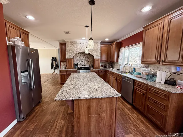 a kitchen with stainless steel appliances granite countertop a refrigerator a sink dishwasher a stove and white countertops with wooden floor