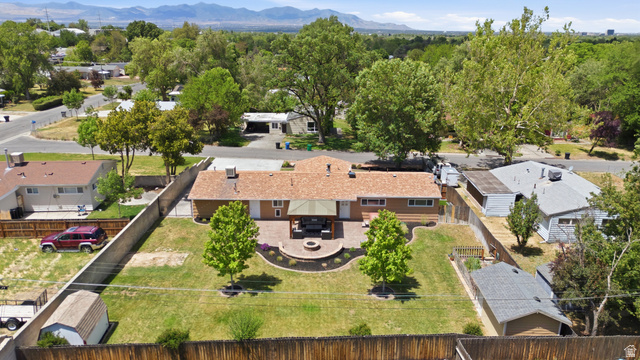 6889 South Village Road Salt Lake City, UT 84121 - Photo 44 of 44 Expansive backyard featuring a stone patio, built-in fire pit, manicured lawn, and mature trees