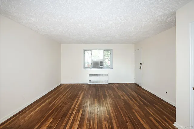 a view of an empty room with wooden floor and window