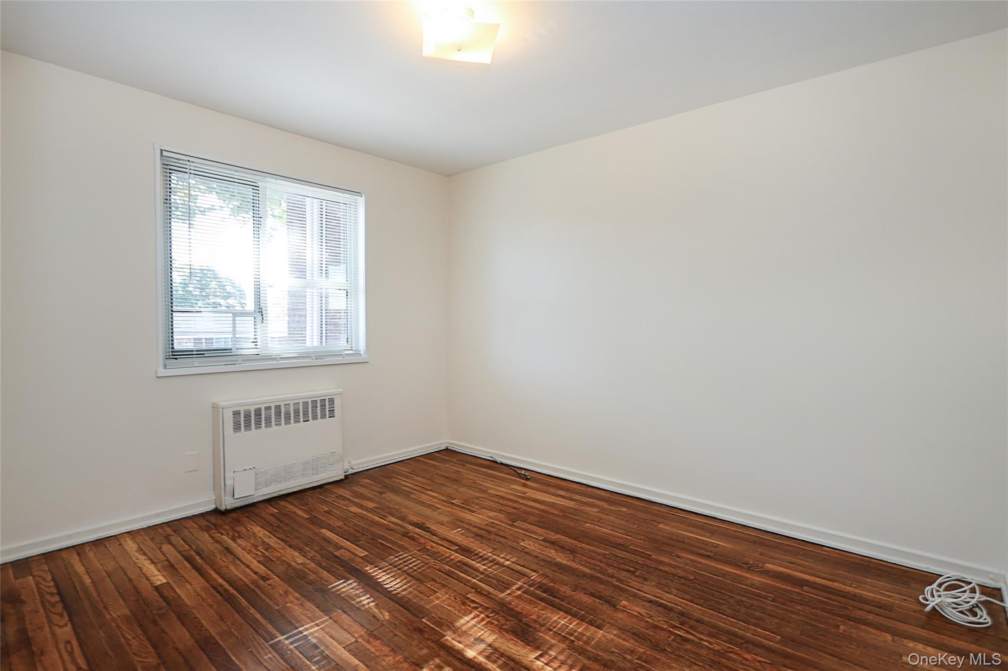 220-04 Stronghurst Avenue, Unit 185 Queens, NY 11427 - Photo 28 of 33 wooden floor in an empty room with a window