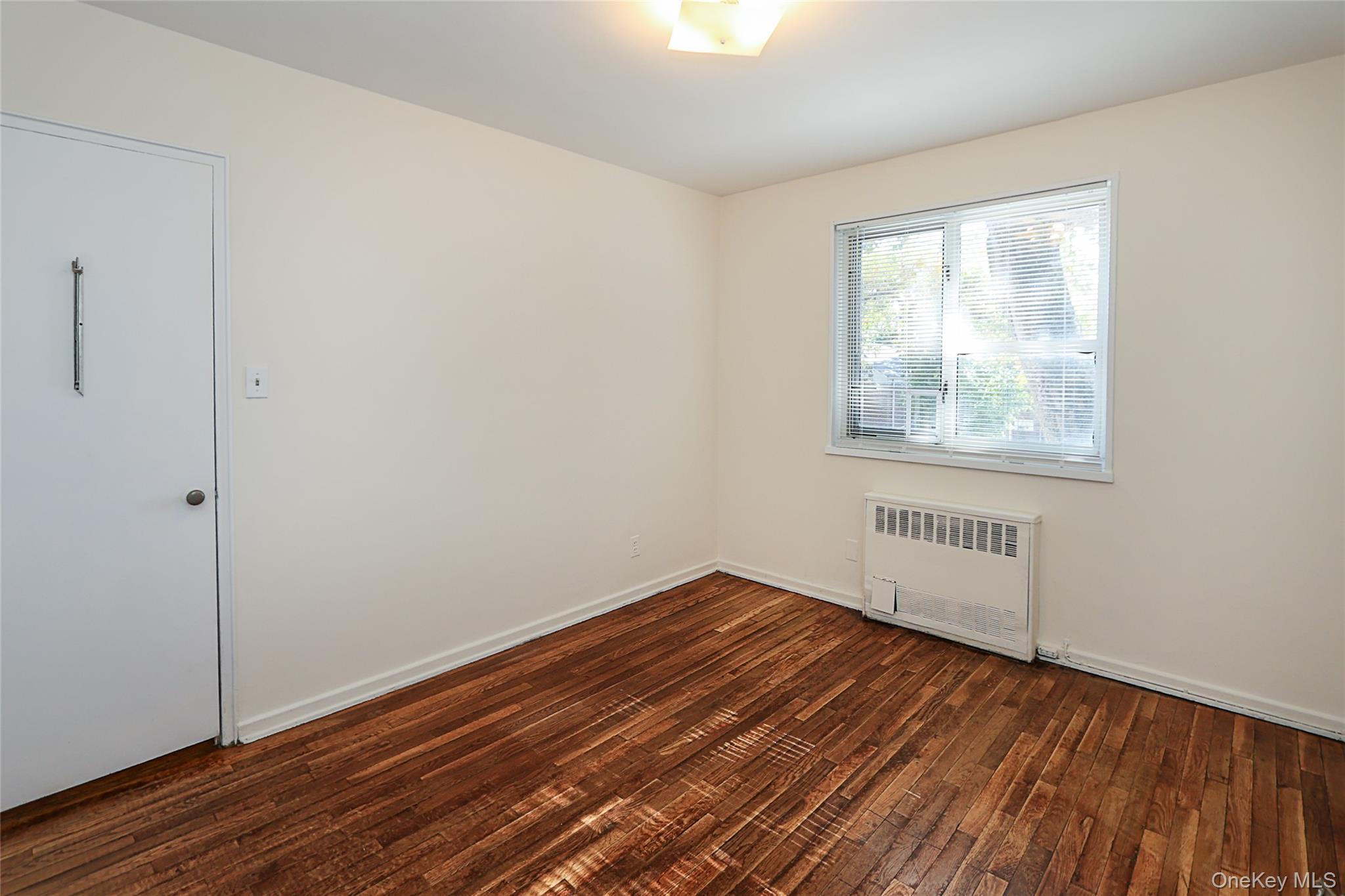 220-04 Stronghurst Avenue, Unit 185 Queens, NY 11427 - Photo 29 of 33 a view of an empty room with wooden floor and a window