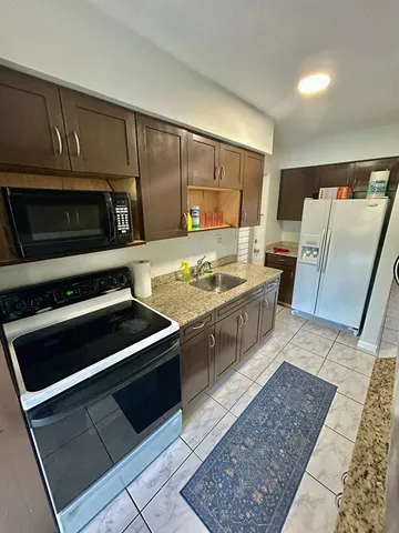 a kitchen with stainless steel appliances granite countertop a stove a sink and a microwave