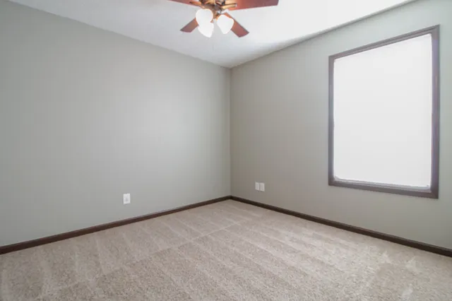 an empty room with a window and a ceiling fan