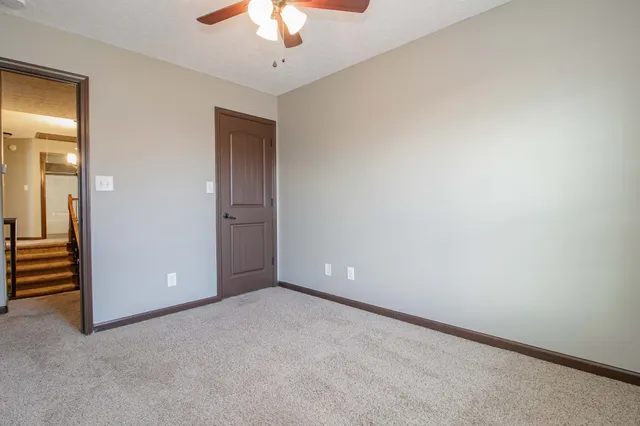 an empty room with a chandelier fan and windows