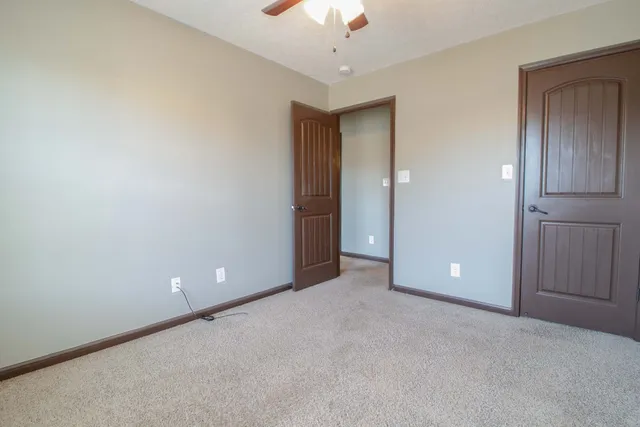 a view of an empty room and chandelier fan