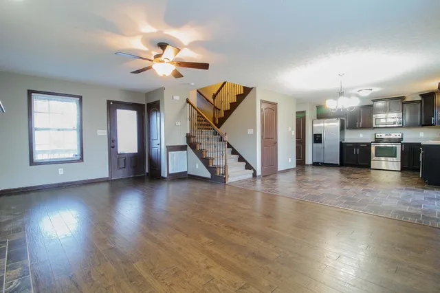a view of a livingroom with wooden floor a ceiling fan and windows