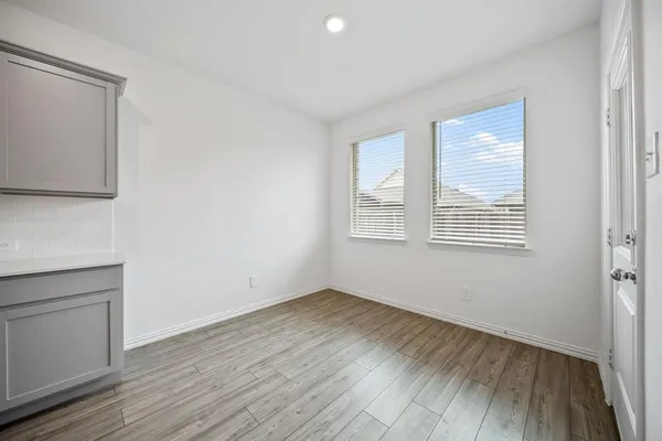 a large white kitchen with kitchen island a sink dishwasher a refrigerator and white cabinets with wooden floor