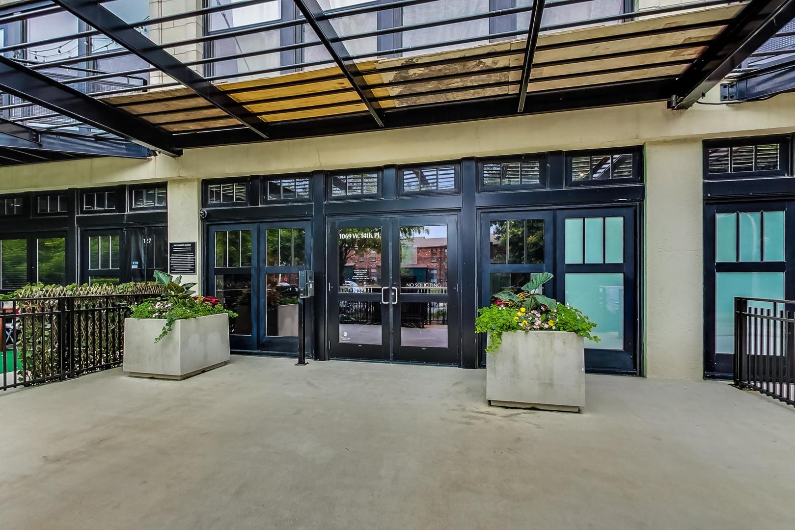 1069 West 14th Place, Unit 228 Chicago, IL 60608 - Photo 3 of 20 a building with potted plants in front of it