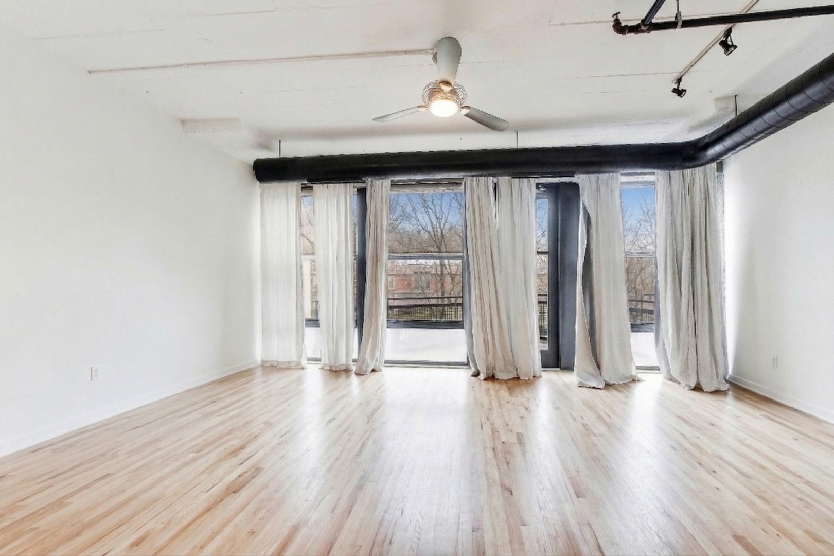 1069 West 14th Place, Unit 228 Chicago, IL 60608 - Photo 4 of 20 a view of wooden floor and windows in a room