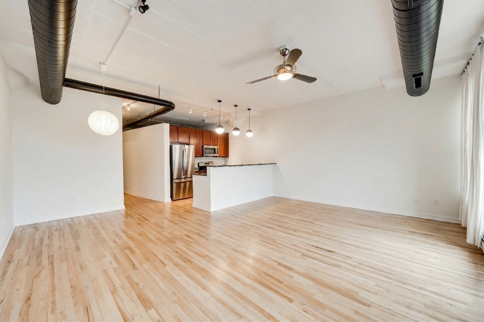 1069 West 14th Place, Unit 228 Chicago, IL 60608 - Photo 7 of 20 a view of a room with wooden floor and white walls