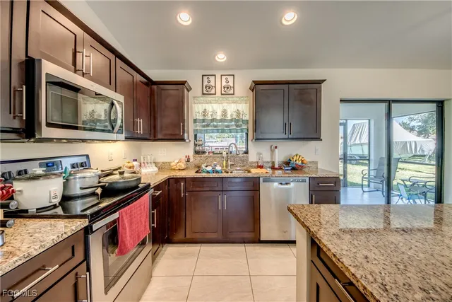 a kitchen with stainless steel appliances granite countertop a stove a sink and a microwave