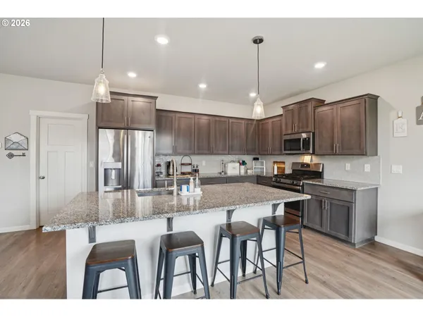 a kitchen with kitchen island granite countertop a sink cabinets and stainless steel appliances