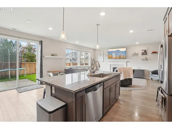 a kitchen with stainless steel appliances granite countertop a sink a stove and a wooden floors