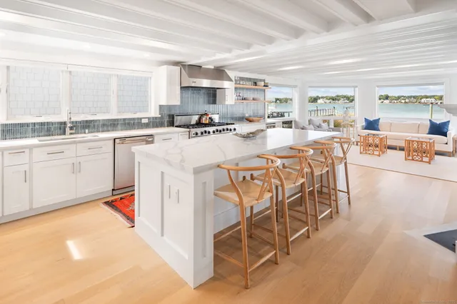 a kitchen with stainless steel appliances kitchen island granite countertop a table chairs sink and cabinets
