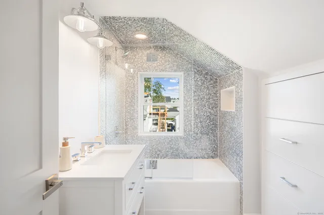 a bathroom with a tub sink and mirror
