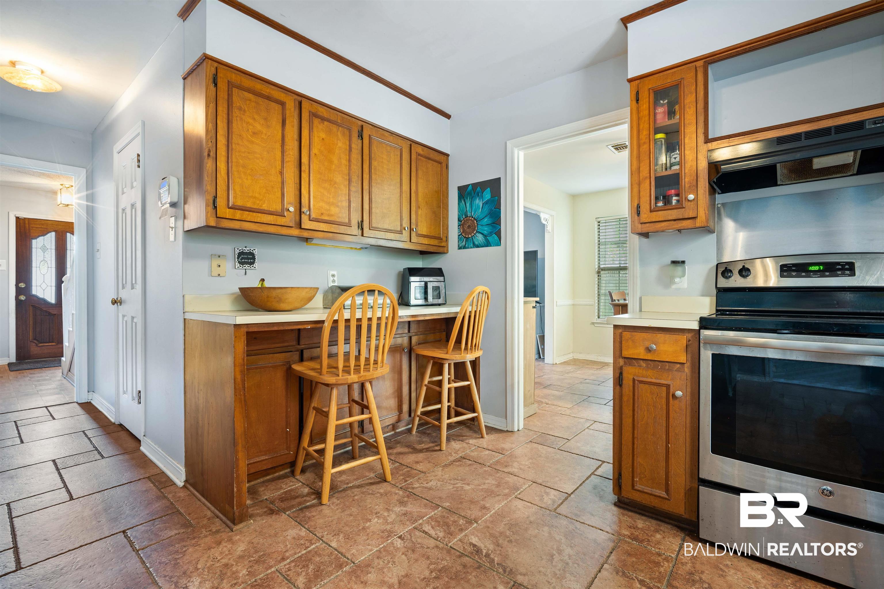 2823 Woodland Road Mobile, AL 36693 - Photo 8 of 29 Kitchen with brown cabinets, stone tile floors, stainless steel electric range oven, light countertops, and baseboards