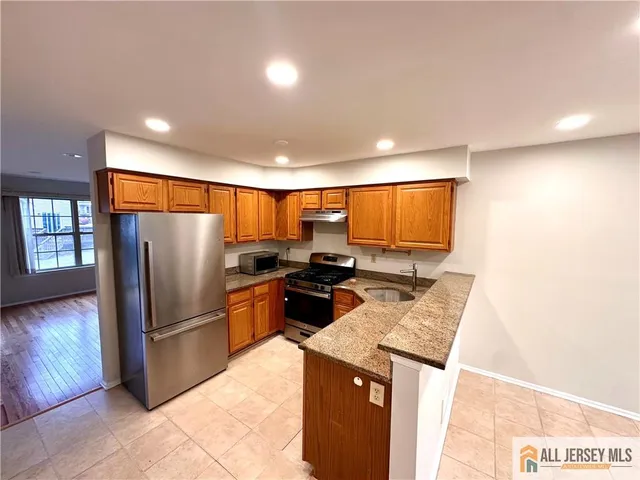 a kitchen with stainless steel appliances granite countertop a refrigerator a sink a stove a microwave a counter top and living room view