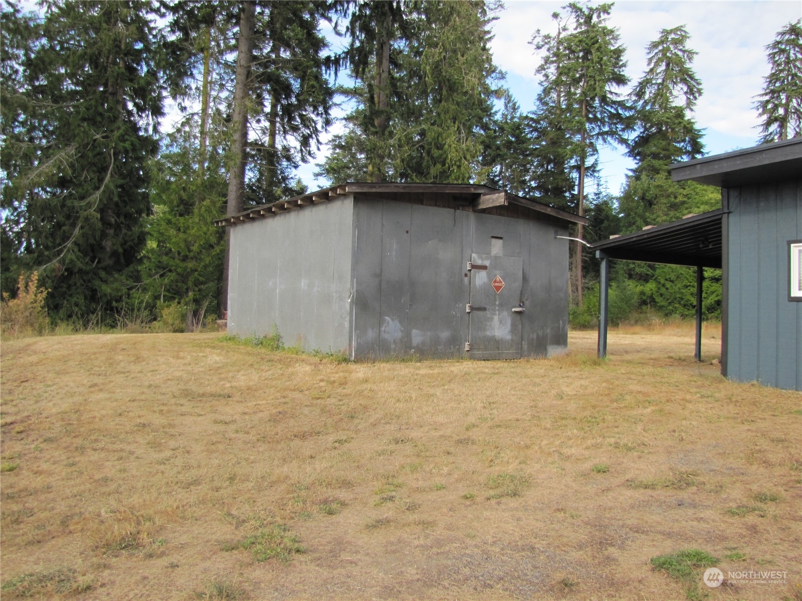 726 Lake Farm Road Port Angeles, WA 98362 - Photo 17 of 24 a backyard of a house with large trees and a wooden bench